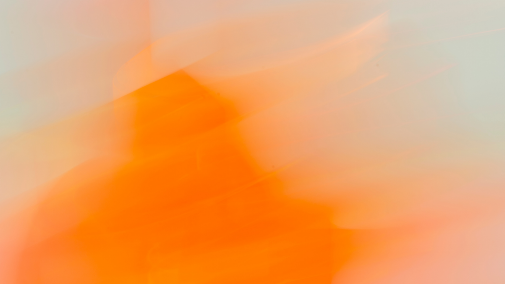 A profile portrait of a woman with long, dark hair, wearing a dark leather jacket. The image is dominated by a deep, monochromatic red light that illuminates the subject's face and creates a distinct spotlight effect against the red background, leaving the rest of her in silhouette.